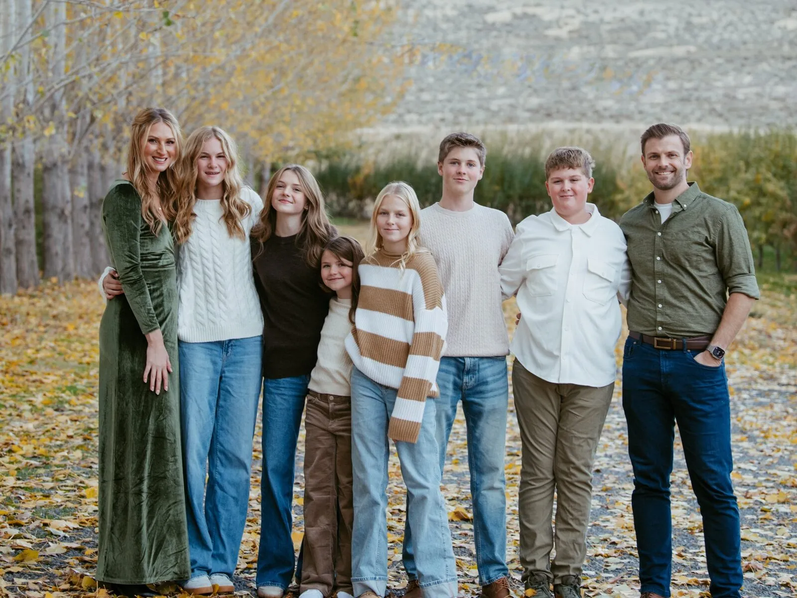Dean Christensen with his wife and six kids under fall poplars near Ephrata, with sagebrush hills behind them